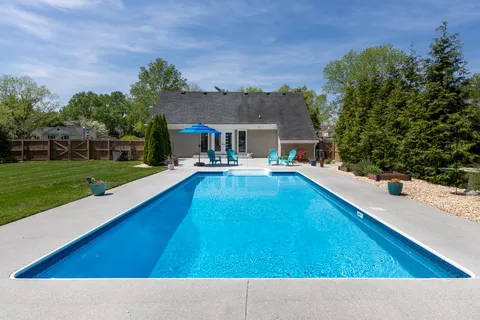 a view of a swimming pool with chairs and table in the patio