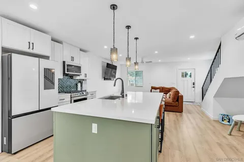 a kitchen with stainless steel appliances a refrigerator a sink a stove a microwave a center island and chairs