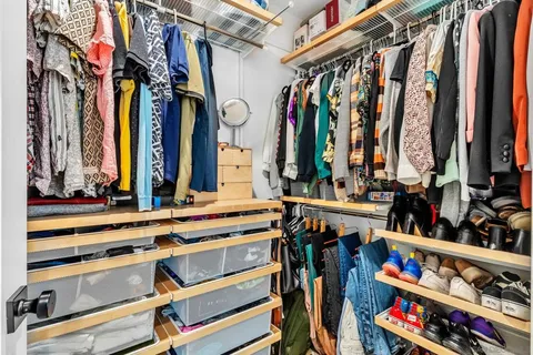 a view of walk in closet with clothes and shoes