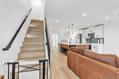 a living room with furniture and a dining table with wooden floor