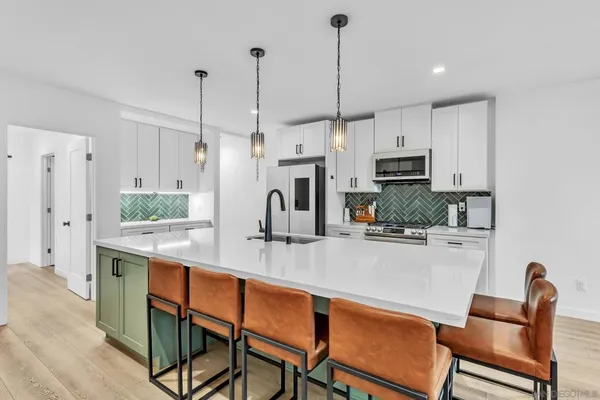 a kitchen with stainless steel appliances kitchen island granite countertop a table chairs and a refrigerator