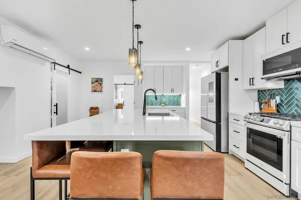 a kitchen with stainless steel appliances granite countertop a refrigerator a stove and white cabinets with wooden floors