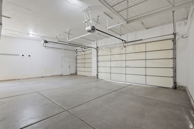 1252 Skyline Road Saratoga Springs, UT 84045 - Photo 43 of 51 Spacious garage featuring two overhead doors, a pedestrian door, a concrete floor, and overhead lighting