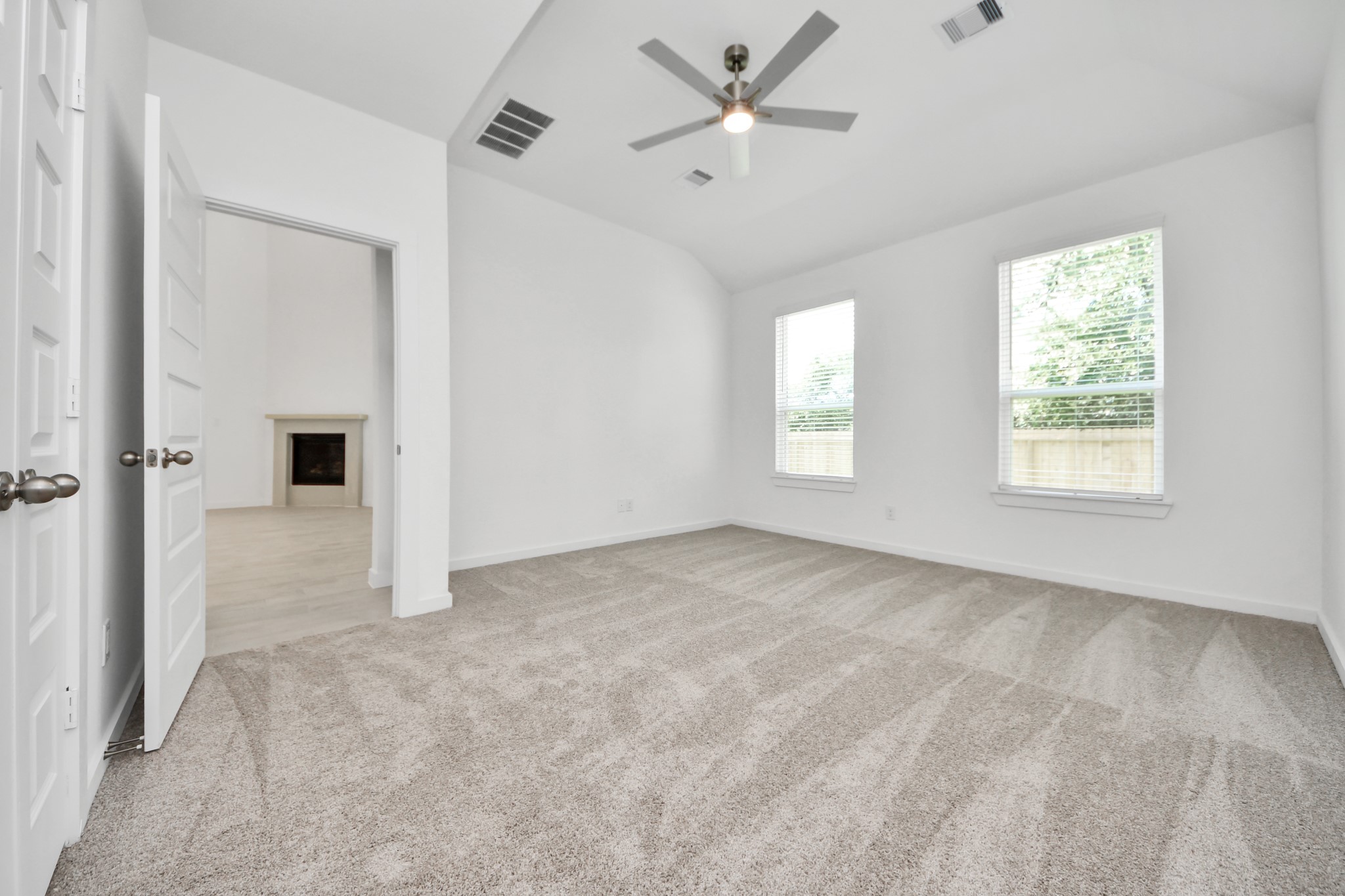 2926 Bury Park Dr Spring Spring, TX 77373 - Photo 19 of 40 Escape and relax in the exquisite primary suite, a haven to unwind after a long day. The spacious room, located on first floor, boasts plush carpeting, soothing paint tones, high ceilings, and expansive windows adorned with privacy blinds.