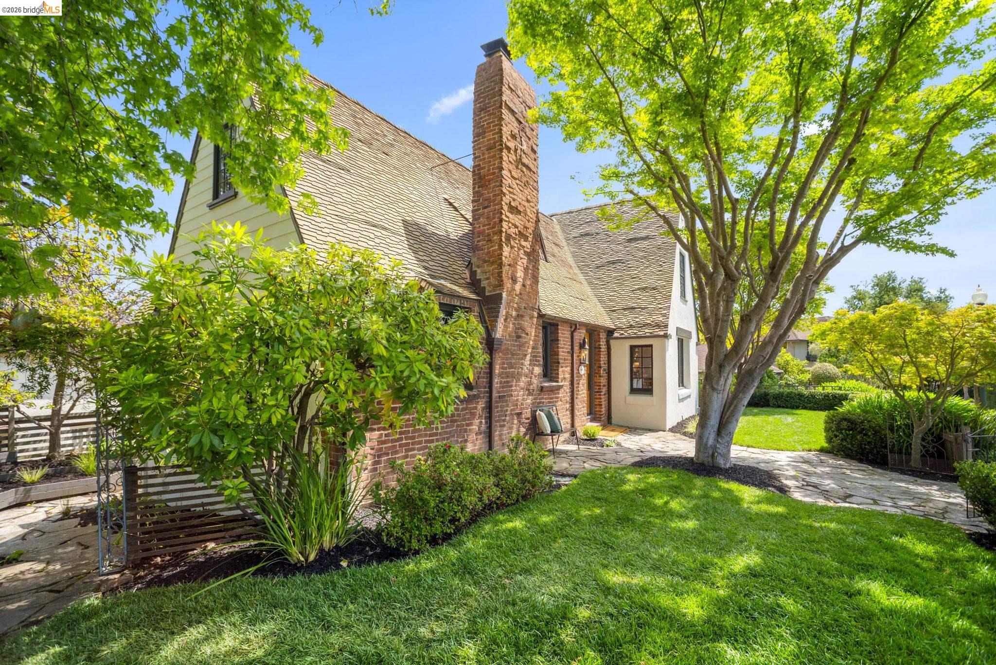 1087 Hubert Road Oakland, CA 94610 - Photo 43 of 67 Exterior brick and stucco residence featuring a prominent brick chimney, gabled roofline, and multiple window placements