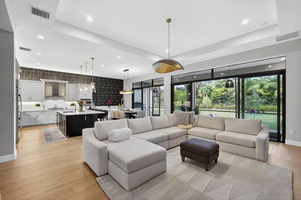 a living room with furniture kitchen area and a large window