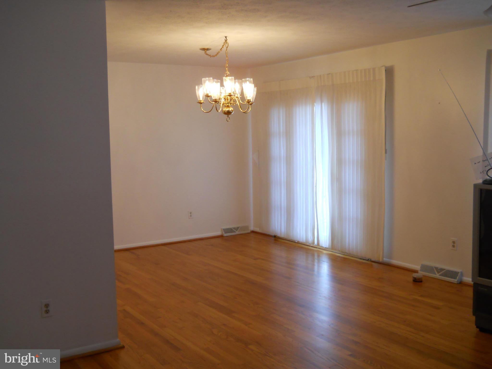 3604 Bellmore Road Baltimore, MD 21244 - Photo 9 of 19 an empty room with wooden floor and chandelier