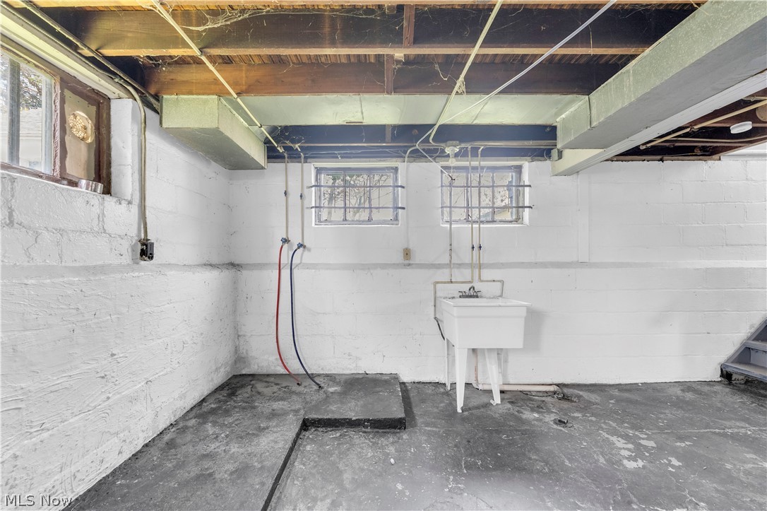 18123 McCracken Road Maple Heights, OH 44137 - Photo 24 of 27 Unfinished basement featuring painted block walls, exposed wood ceiling joists, concrete flooring, and a utility sink