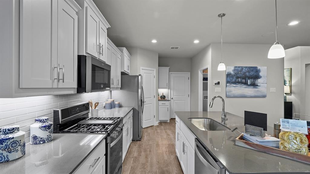 15540 Balham Path Fort Worth, TX 76247 - Photo 2 of 40 a kitchen with stainless steel appliances granite countertop a stove top oven a sink dishwasher a refrigerator white cabinets and wooden floor