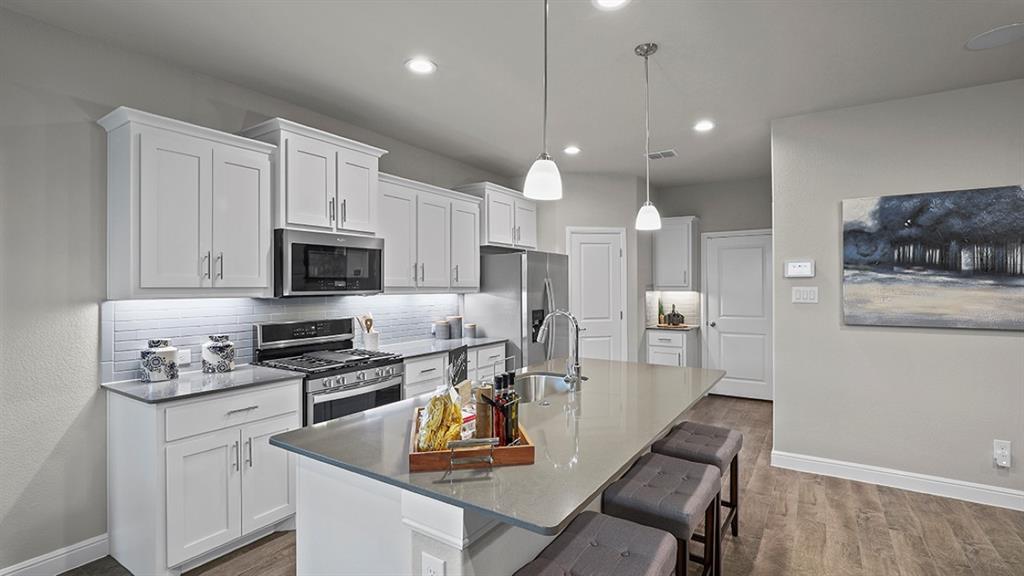 15540 Balham Path Fort Worth, TX 76247 - Photo 4 of 40 a kitchen with stainless steel appliances kitchen island granite countertop a stove a sink a microwave a refrigerator and white cabinets with wooden floor