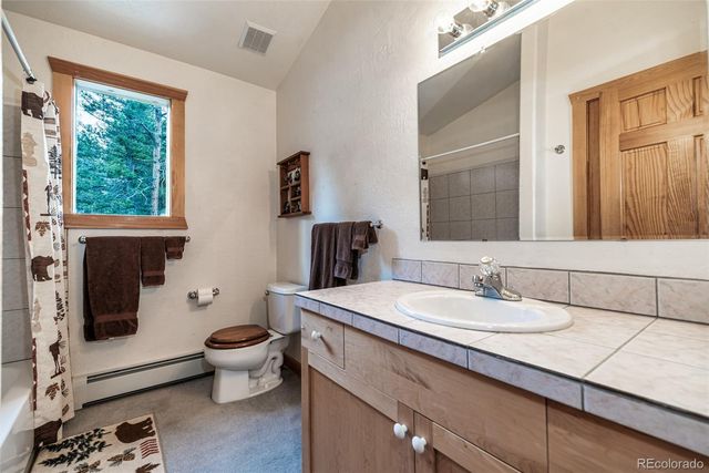 a bathroom with a granite countertop toilet a sink and a mirror