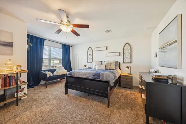 a bedroom with a bed couch chandelier and a window