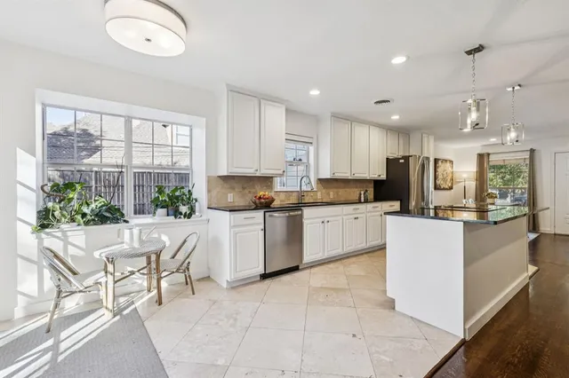 a kitchen with kitchen island granite countertop a stove a sink a refrigerator and white cabinets with wooden floor