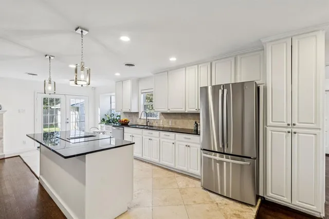 a kitchen with stainless steel appliances granite countertop a refrigerator a sink and white cabinets