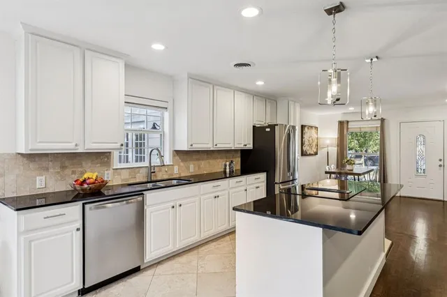 a kitchen with stainless steel appliances granite countertop a sink refrigerator and cabinets