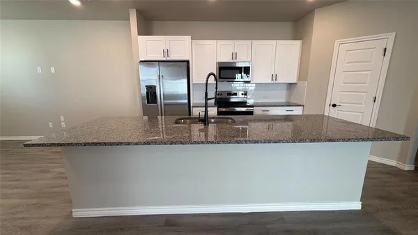 a kitchen with granite countertop a sink a stove and refrigerator