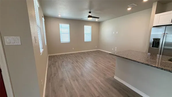 an empty room with wooden floor and windows