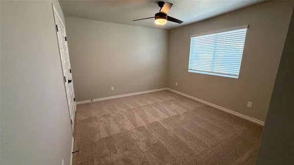 an empty room with a window and a ceiling fan