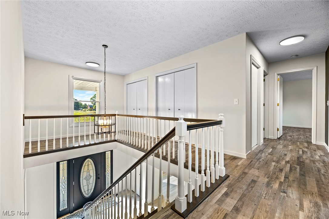 2236 Hartville Road Mogadore, OH 44260 - Photo 25 of 50 Hall with a textured ceiling, hardwood / wood-style flooring, a chandelier, and an upstairs landing