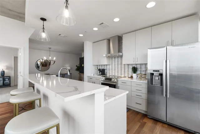 a kitchen with stainless steel appliances granite countertop a table chairs refrigerator and sink