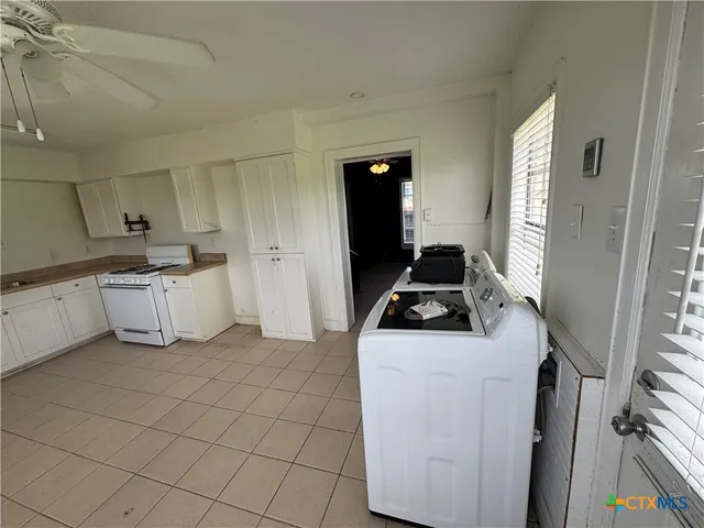 a view of a kitchen with kitchen island white cabinets and refrigerator