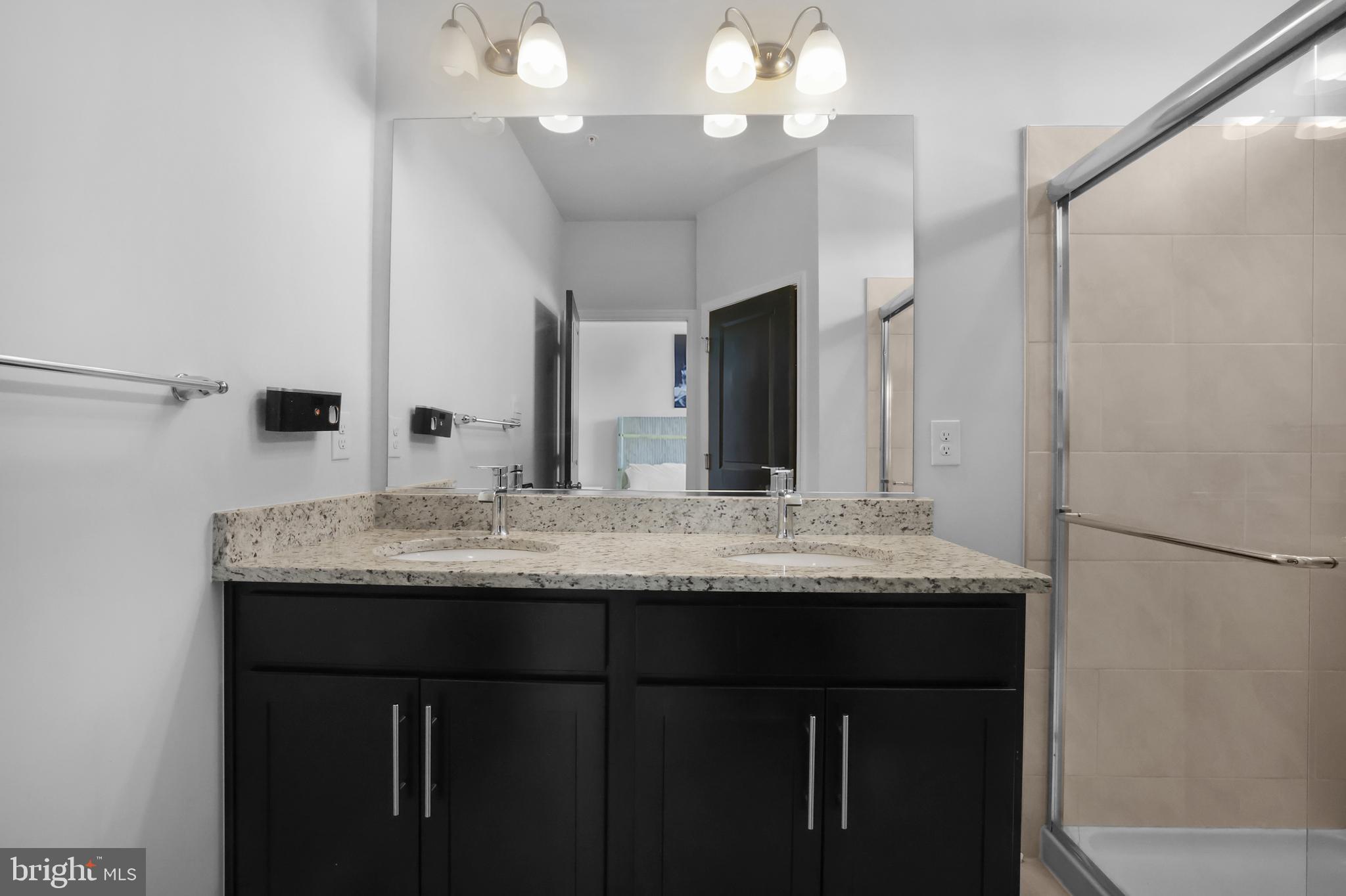 854 Amity Street Frederick, MD 21701 - Photo 23 of 62 a bathroom with a granite countertop sink a large mirror and a shower