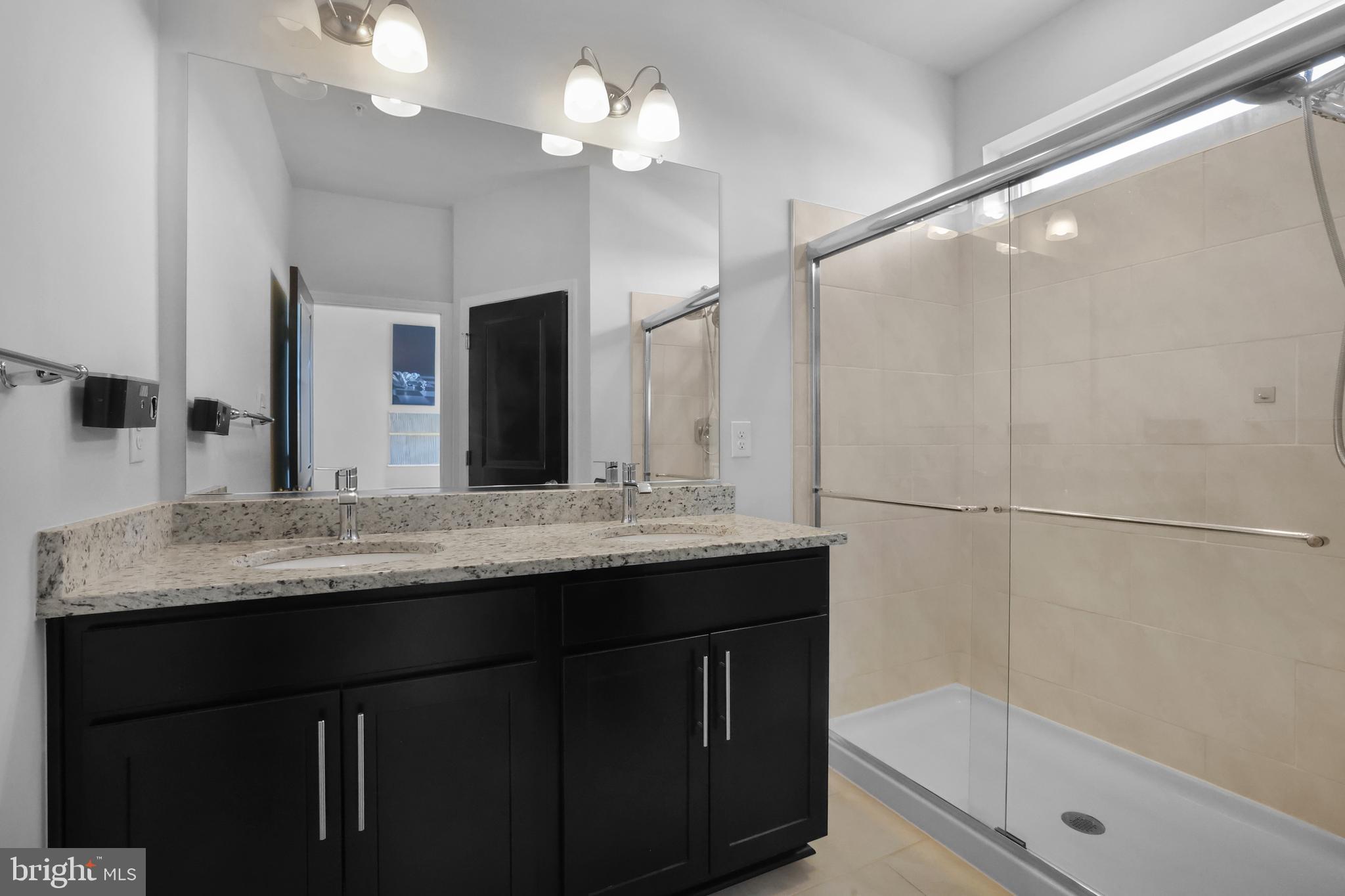 854 Amity Street Frederick, MD 21701 - Photo 24 of 62 a bathroom with a granite countertop sink a large mirror and a shower