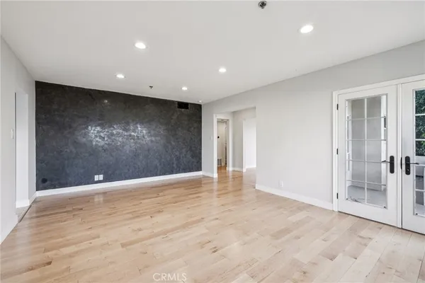 an empty room with wooden floor fireplace and windows