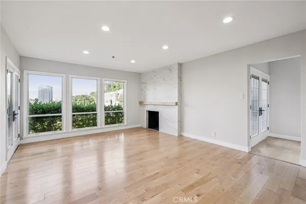 a view of an empty room with wooden floor and a fireplace