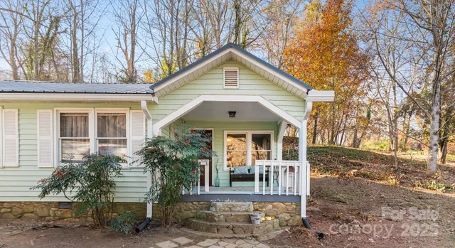 a view of a white house next to a yard with large trees