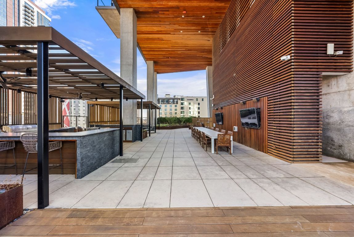 70 Rainey Street, Unit 2606 Austin, TX 78701 - Photo 30 of 37 a view of a patio with dining table and chairs with wooden floor and fence