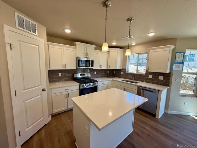 a kitchen with stainless steel appliances white cabinets a sink a stove a refrigerator and island