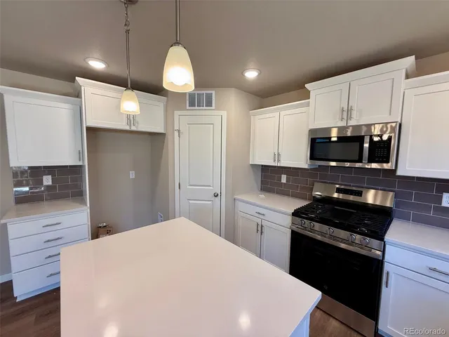 a kitchen with granite countertop a stove cabinets and refrigerator