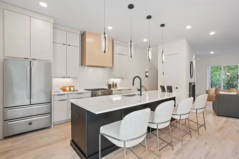 a kitchen with stainless steel appliances granite countertop a table chairs sink refrigerator and cabinets