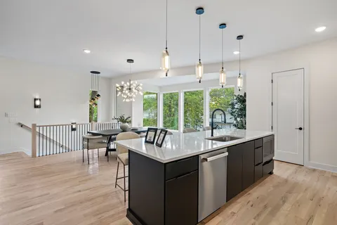 a kitchen with kitchen island granite countertop a sink and a living room view