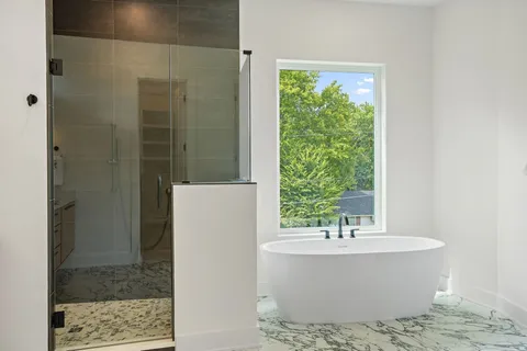 a white bath tub sitting in a bathroom next to a window