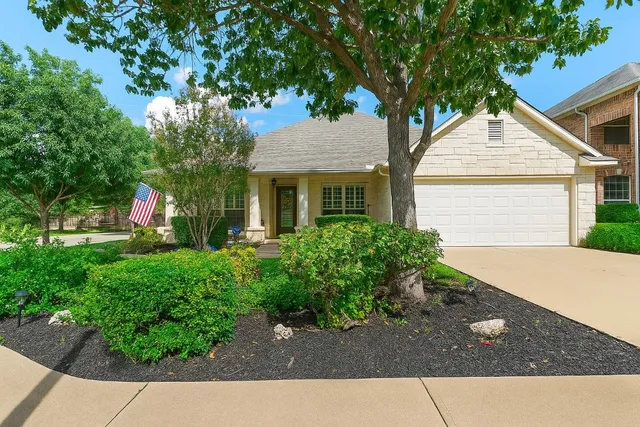 a view of a white house next to a yard with plants and trees