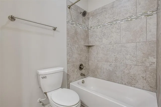 a white toilet sitting next to a bath tub and a shower