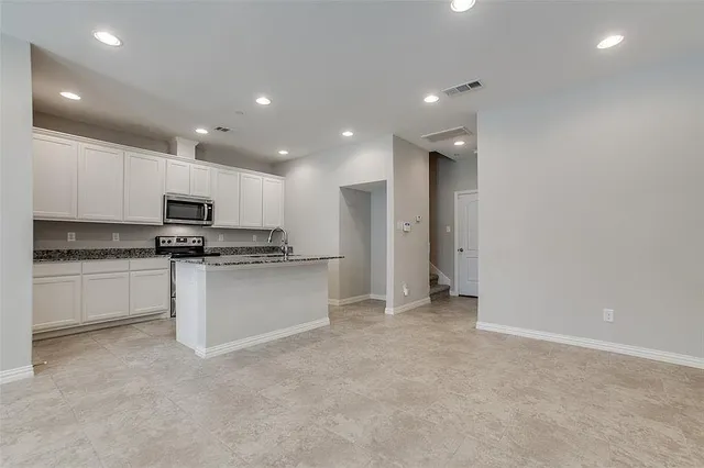 a view of kitchen with granite countertop cabinets and refrigerator