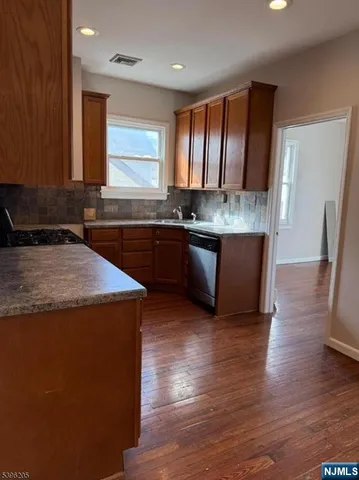 a kitchen with stainless steel appliances granite countertop a sink stove and wooden floor
