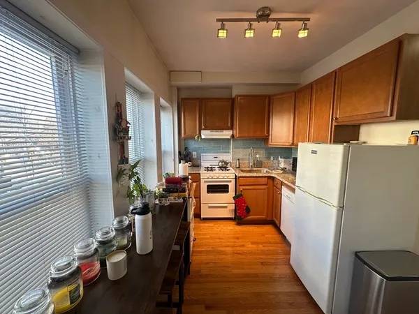 a kitchen with sink a refrigerator and wooden cabinets