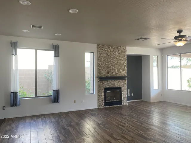 an empty room with windows a fireplace and wooden floor