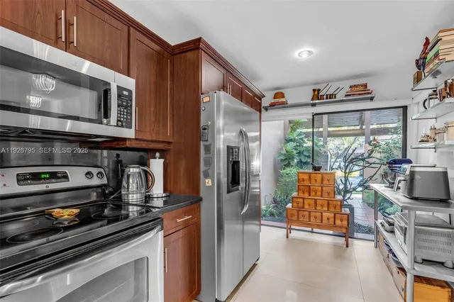 a kitchen with stainless steel appliances granite countertop a refrigerator a stove and a sink with wooden floor