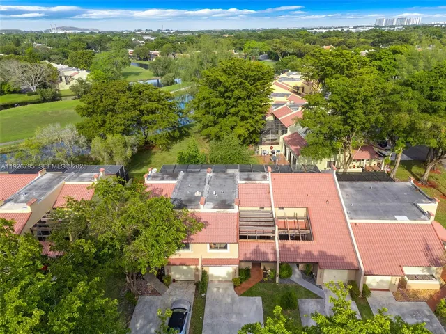 an aerial view of residential houses with outdoor space and trees