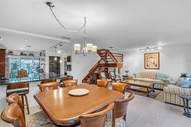 a living room with furniture kitchen view and a chandelier