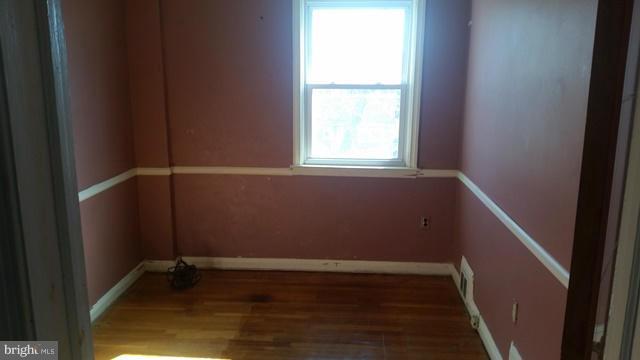 1215 Cedarcroft Road Baltimore, MD 21239 - Photo 3 of 11 a view of an empty room with wooden floor and a window