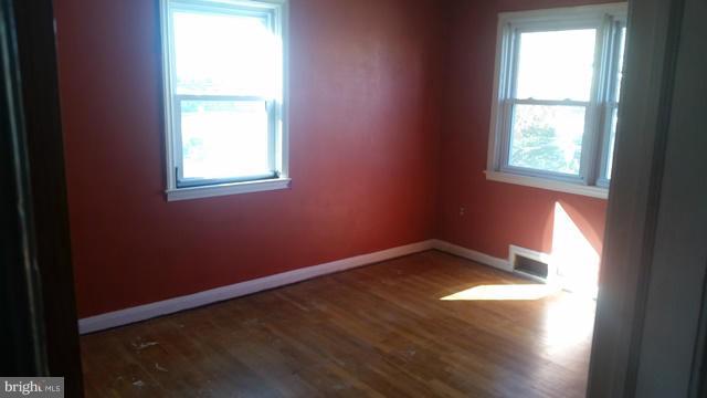 1215 Cedarcroft Road Baltimore, MD 21239 - Photo 5 of 11 an empty room with wooden floor and windows