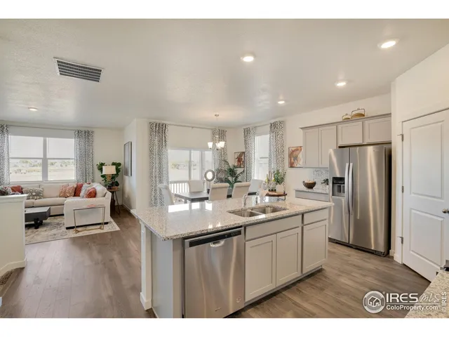 a kitchen with stainless steel appliances granite countertop a sink dishwasher a refrigerator and white cabinets with wooden floor