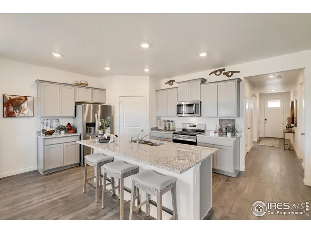 a kitchen with stainless steel appliances kitchen island granite countertop a refrigerator a stove a sink a dining table and chairs