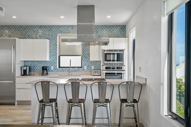 a kitchen with stainless steel appliances granite countertop a table chairs and a refrigerator